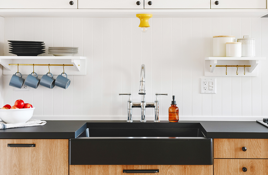 Moderna cocina con gabinetes de madera, tarja, cubiertas negras y accesorios de cocina
